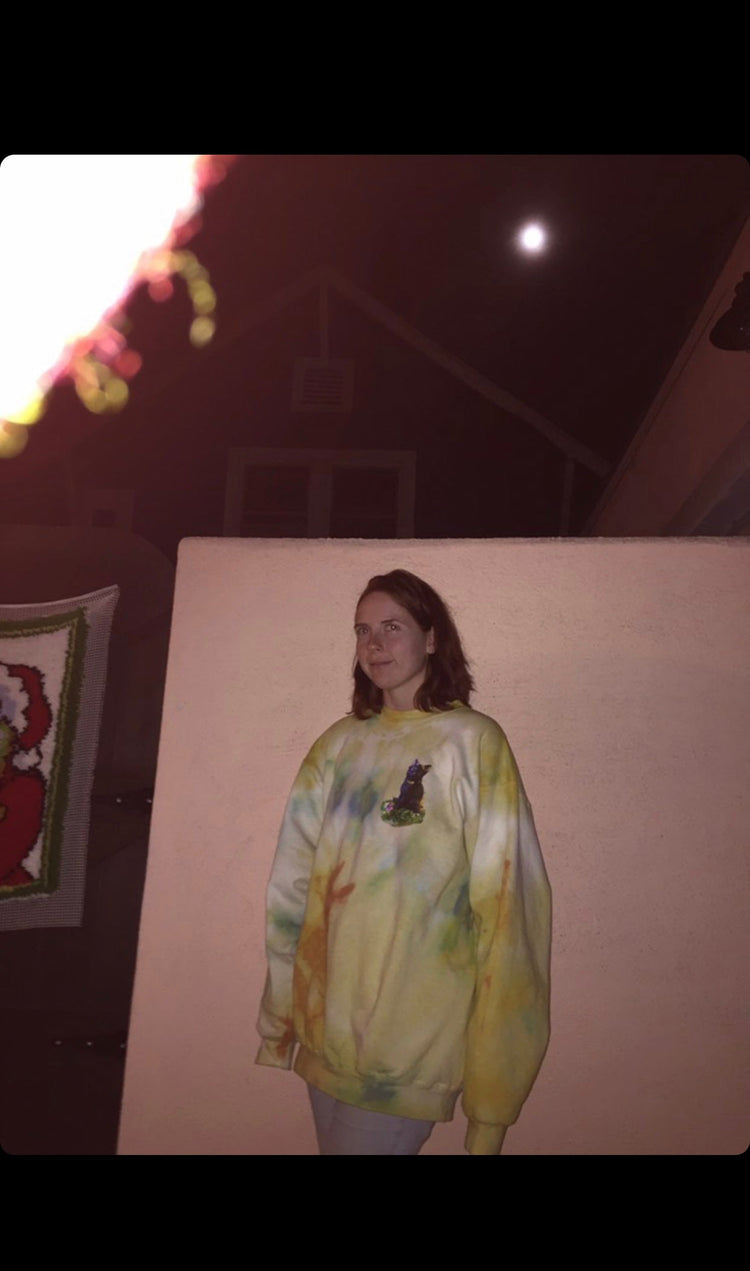 Women in custom tie dyed yellow sweatshirt with cat figure